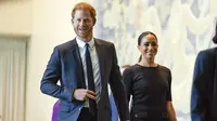 Meghan Markle didampingi suaminya Pangeran Harry tersenyum saat tiba di markas PBB (18/7/2022). Meghan dan Harry tampak kompak mengenakan pakaian serbahitam. (AP Photo/Seth Wenig)