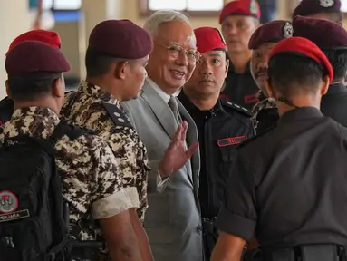Mantan Perdana Menteri Malaysia, Najib Razak (tengah) dikawal oleh petugas penjara saat tiba di Kompleks Pengadilan Tinggi Kuala Lumpur, Malaysia, Senin 22 Desember 2025. Mahkamah Tinggi Kuala Lumpur pada Senin 22 Desember 2025 menolak permohonan mantan Perdana Menteri Malaysia, Najib Razak, untuk menjalani sisa masa hukumannya sebagai tahanan rumah. (AP Photo/Azneal Ishak)