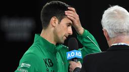 Petenis Serbia, Novak Djokovic, menangis saat diwawancara tentang Kobe Bryant seusai laga Australia Open 2020 di Melbourne, Selasa (28/1). Beri penghormatan dirinya memakai jaket inisial Kobe Bryant. (AFP/Greg Wood)