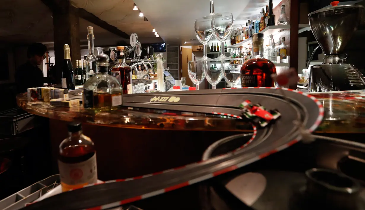 Pekerja menghabiskan waktu dengan bermain lintasan mobil balap mainan yang dipasang di sebuah bar di Praha, Republik Ceko, 15 Oktober 2020. Area bar menjadi lintasan mobil mainan yang bisa dimanfaatkan para karyawan untuk mengusir kebosanan saat menunggu pesanan. (AP Photo/Petr David Josek)