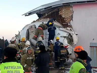 Petugas penyelamat di antara puing-puing  pesawat maskapai Bek Air di dekat Bandara Almaty, Kazakhstan, Jumat (27/12/2019). Pesawat kehilangan ketinggian sebelum menabrak pembatas kokoh dan menghantam bangunan dua lantai. (Emergency Situations Ministry of the Republic of Kazakhstan photo via AP)
