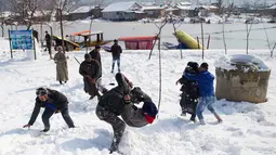 Sejumlah pria bermain di lapangan yang tertutup salju di Srinagar, kawasan Kashmir yang dikuasai India, Sabtu (5/1). Wilayah Kashmir mengalami salju selama beberapa hari yang mengakibatkan terputus jalan raya Jammu-Srinagar (AP Photo/Dar Yasin)