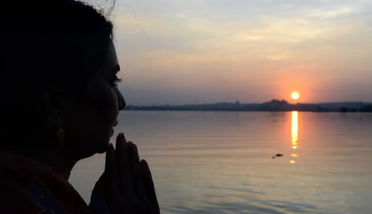 Seorang perempuan Hindu India memanjatkan doa pada matahari saat festival Chhath di tepi Danau Hussain Sagar di Hyderabad, Selasa (17/11). Dalam festival tersebut, sejumlah umat Hindu berdoa saat matahari terbit dan tenggelam. (AFP PHOTO/NOAH Seelam)