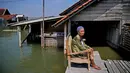 Mar'iah duduk di luar rumahnya sambil menunggu air banjir surut di Timbulsloko, Jawa Tengah, Indonesia, 31 Juli 2022. Mar'iah menjelaskan bahwa dia duduk di kursi setiap hari menunggu sampai rumahnya cukup kering untuk masuk lagi. (AP Photo/Dita Alangkara)