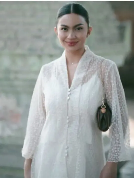 Ariel Tatum tampil serba putih, mengenakan atasan kebaya modern bermotif transparan dipadukan inner spaghetti strap warna senada. Tampak ia pun membawa shoulder bag hitam. [@arieltatum]