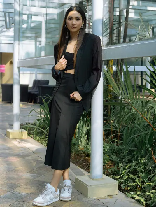 Outfit kantoran yang chic dari Mikha Tambayong. Ia mengenakan cropped top yang ditumpuknya dengan blazer dan midi skirt serba hitam, serta sentuhan sneakers putih yang mempermanis seluruh penampilannya.  [Foto: Instagram/miktambayong]