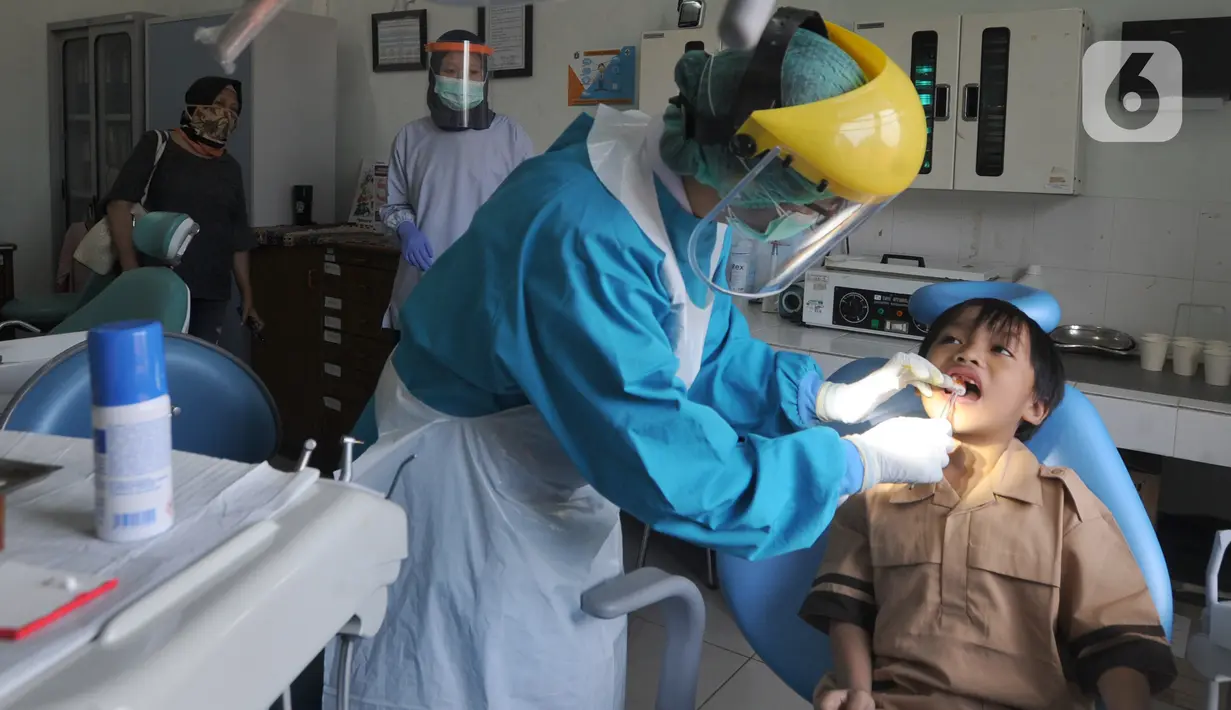 Dokter mencabut gigi murid baru sekolah dasar negeri di Puskesmas Pondok Labu, Jakarta Selatan, Rabu (12/8/2020). Selain dalam rangka Bulan Imunisasi Anak Sekolah, kegiatan ini juga bagian dari pemeriksaan kesehatan menyeluruh kepada murid baru sekolah dasar negeri. (merdeka.com/Arie Basuki)