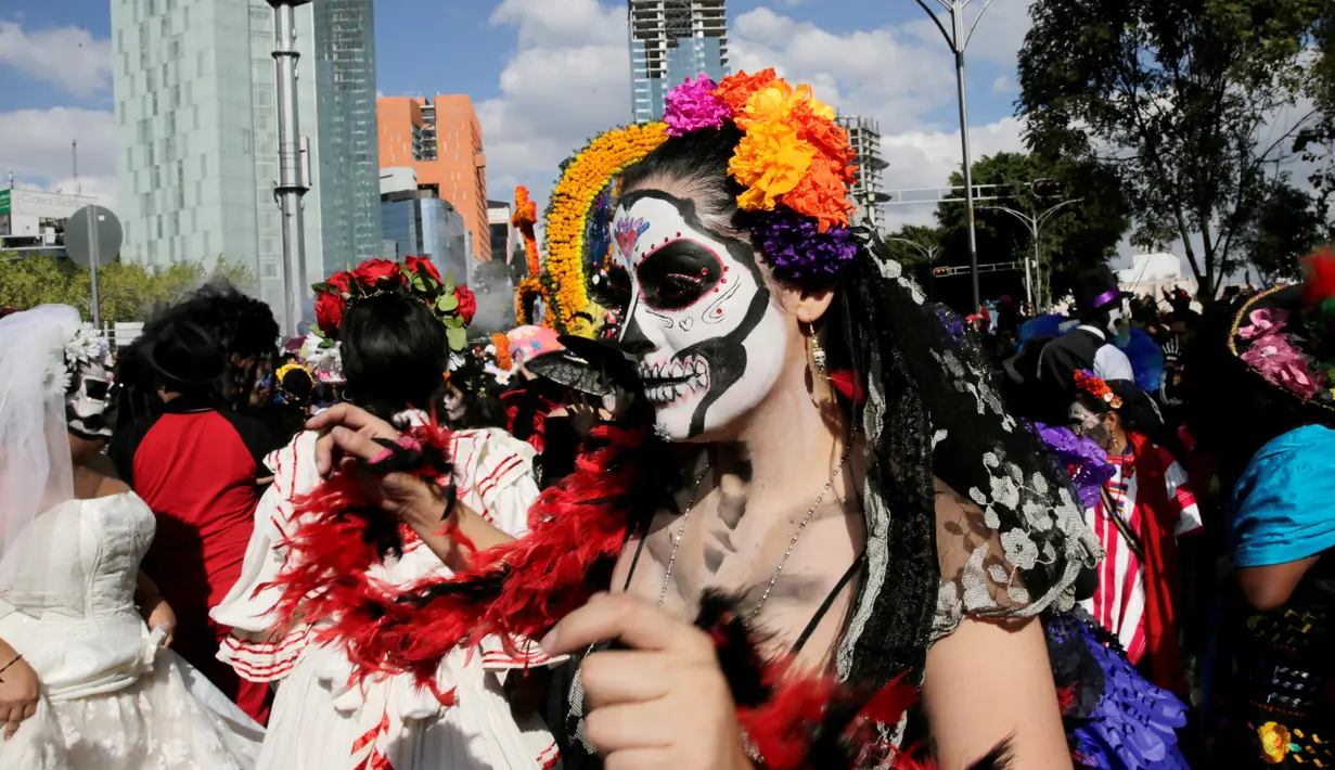 Seorang wanita menghias wajahnya saat parade "Day of the Dead" di Mexico City, Meksiko, Sabtu, (29/10). Festival Kematian bertujuan untuk mengenang dan menghormati orang-orang yang telah meninggal. (REUTERS / Carlos Jasso)