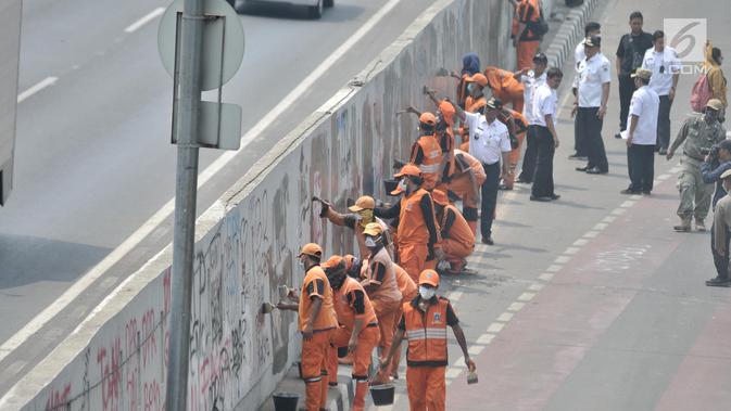 Petugas PPSU membersihkan coretan yang mengotori tembok di kawasan Gedung DPR, Jakarta, Rabu (25/9/2019). Demonstrasi mahasiswa yang berujung ricuh yang berujung kerusuhan tersebut menyebabkan fasilitas umum rusak dan penuh coretan yang dibuat oleh pendemo. (merdeka.com/Iqbal S Nugroho)