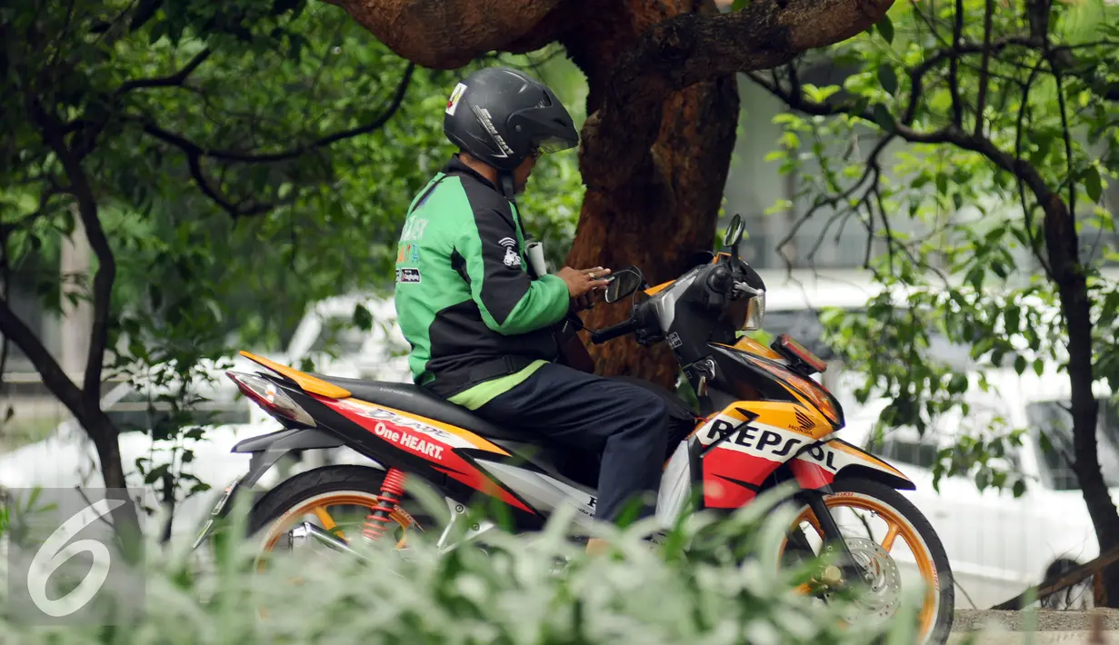 Pengendara ojek online melihat daftar orderan di Jalan Protokol Halim Perdanakusuma, Jakarta, Jumat (18/12/2015). Setelah sempat dilarang pengoperasiannya, kini ojek on line diperbolehkan beroperasi kembali. (Liputan6.com/Helmi Fithriansyah)