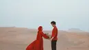 Dinda Hauw dan Rey Mbayang terlihat begitu kompak dengan baju warna merah yang sangat kontras dengan gurun pasir di sekitarnya. (Instagram/dindahw).