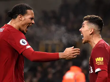 Pemain Liverpool Roberto Firmino (kanan) merayakan golnya ke gawang Wolverhampton Wanderers bersama Virgil van Dijk pada pertandingan Liga Inggris di Molineux Stadium, Wolverhampton, Inggris, Kamis (23/1/2020). Liverpool menang 2-1. (Oli SCARFF/AFP)