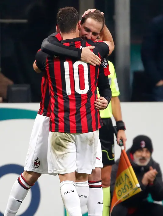 Striker AC Milan, Gonzalo Higuain memeluk gelandang Hakan Calhanoglu usai mencetak gol ke gawang SPAL pada lanjutan Liga Serie A Italia di stadion San Siro (29/12). Gol Higuain memberi kemenangan tipis Milan atas SPAL 2-1. (AP Photo/Antonio Calanni)