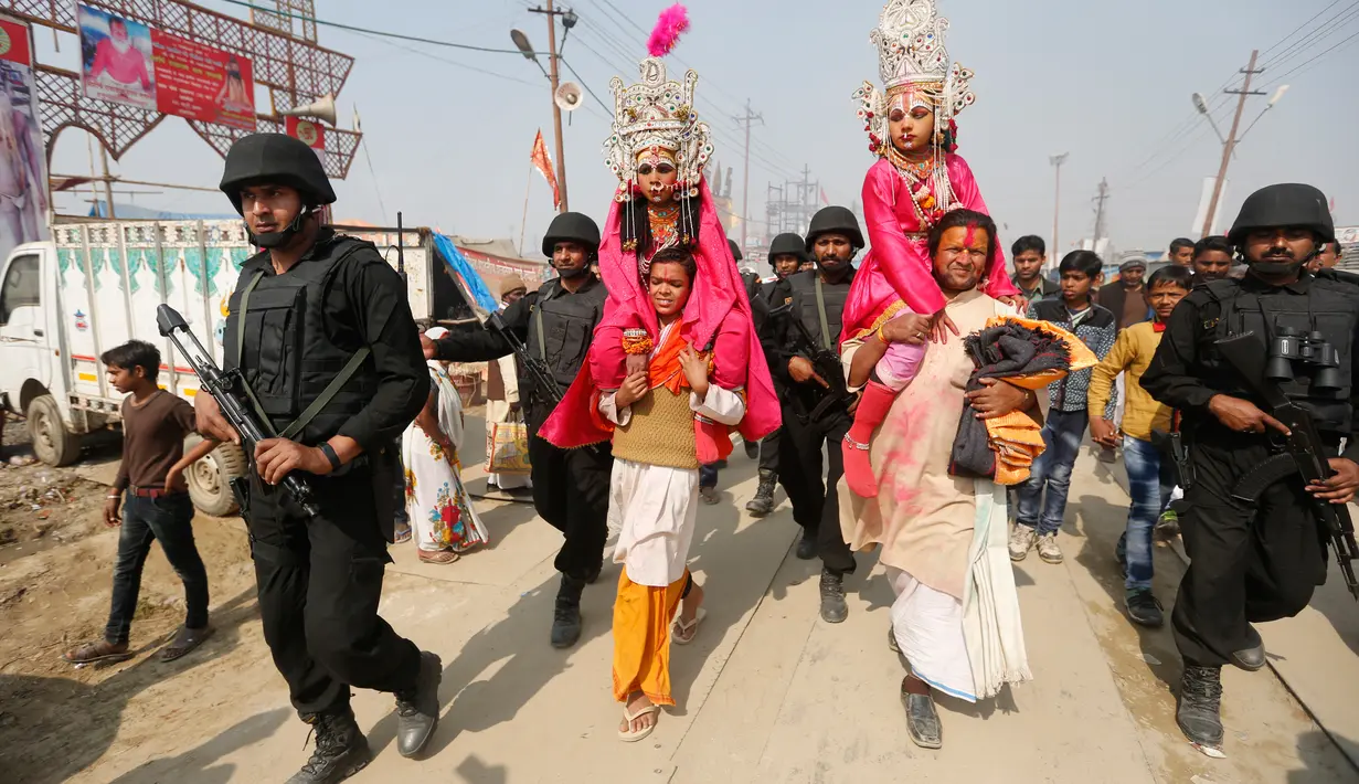 Petugas keamanan berjaga-jaga saat orang suci Hindu membawa anak-anak berpakaian seperti Dewa Rama dan Sita pada ritual Basant Panchami dalam festival tahunan Magh Mela di Allahabad, India, Senin (22/1). (AP Photo/Rajesh Kumar Singh)