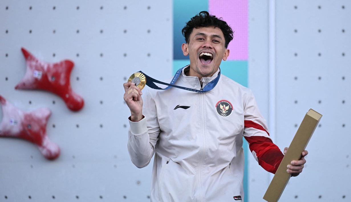 Peraih medali emas dari Indonesia, Veddriq Leonardo, merayakan kemenangannya di atas podium nomor panjat tebing putra dalam ajang panjat tebing nomor kecepatan Olimpiade Paris 2024 di Le Bourget Sport Climbing Venue, Le Bourget, 8 Agustus 2024. (Jonathan NACKSTRAND/AFP)