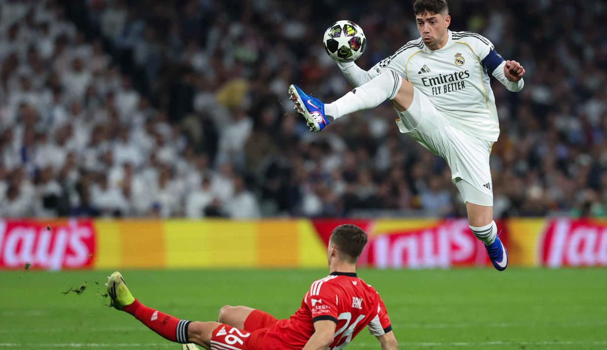 Los Blancos tampil dominan dengan keunggulan yang sudah mereka raih pada pertemuan pertama. Meski demikian, pertandingan berjalan dengan tempo tinggi sejak awal laga. Tampak dalam foto, gelandang Real Madrid asal Uruguay, Federico Valverde (kanan), melompat untuk merebut bola di atas bek SL Benfica asal Swedia, Samuel Dahl, selama pertandingan leg kedua babak playoff 16 besar Liga Champions 2025/2026 di Stadion Santiago Bernabeu pada Rabu 25 Februari 2026 waktu setempat atau Kamis (26/2/2026) dini hari WIB. (Pierre-Philippe MARCOU/AFP)