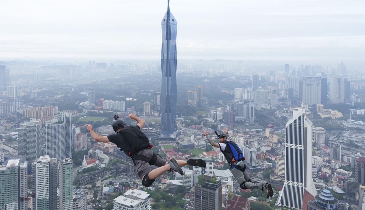 Sepasang pelompat BASE terjun dari Menara Kuala Lumpur selama KL Tower International Jump Malaysia di Kuala Lumpur, Jumat (3/2/2023). Ini merupakan salah satu olahraga ekstrim yang memicu adrenalin dan membuat penasaran para pengunjung. (AP Photo/Vincent Thian)
