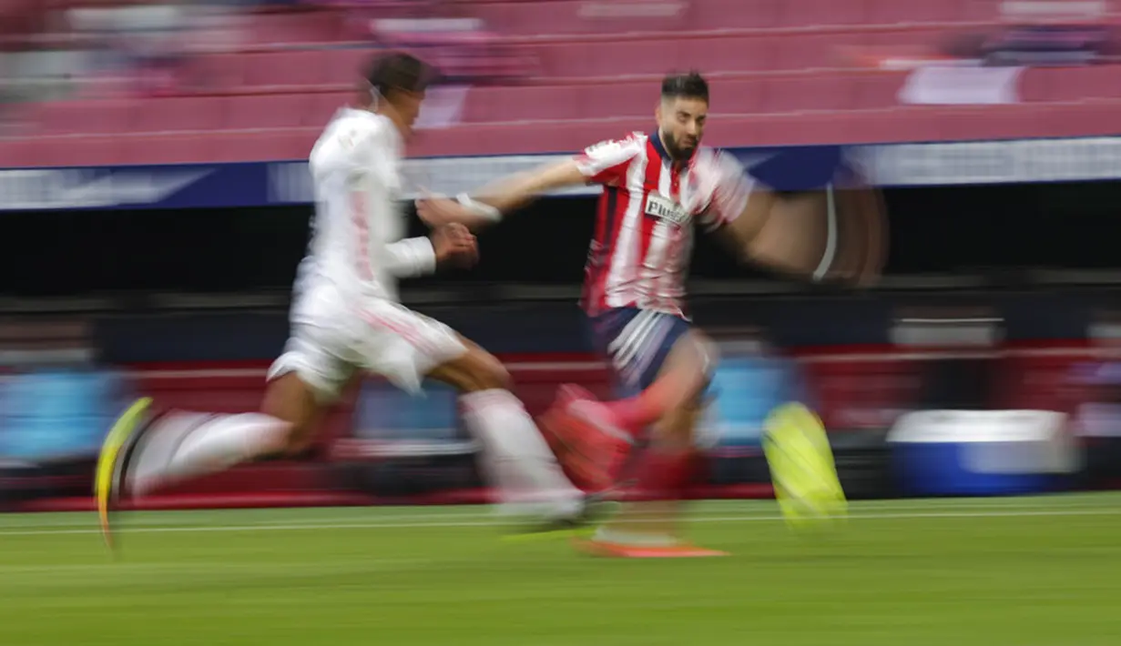 Pemain Real Madrid Raphael Varane (kiri) memperebutkan bola dengan pemain Atletico Madrid Yannick Carrasco pada pertandingan Liga Spanyol di Stadion Wanda Metropolitano, Madrid, Spanyol, Minggu (7/3/2021). Pertandingan berakhir dengan skor 1-1. (AP Photo/Manu Fernandez)