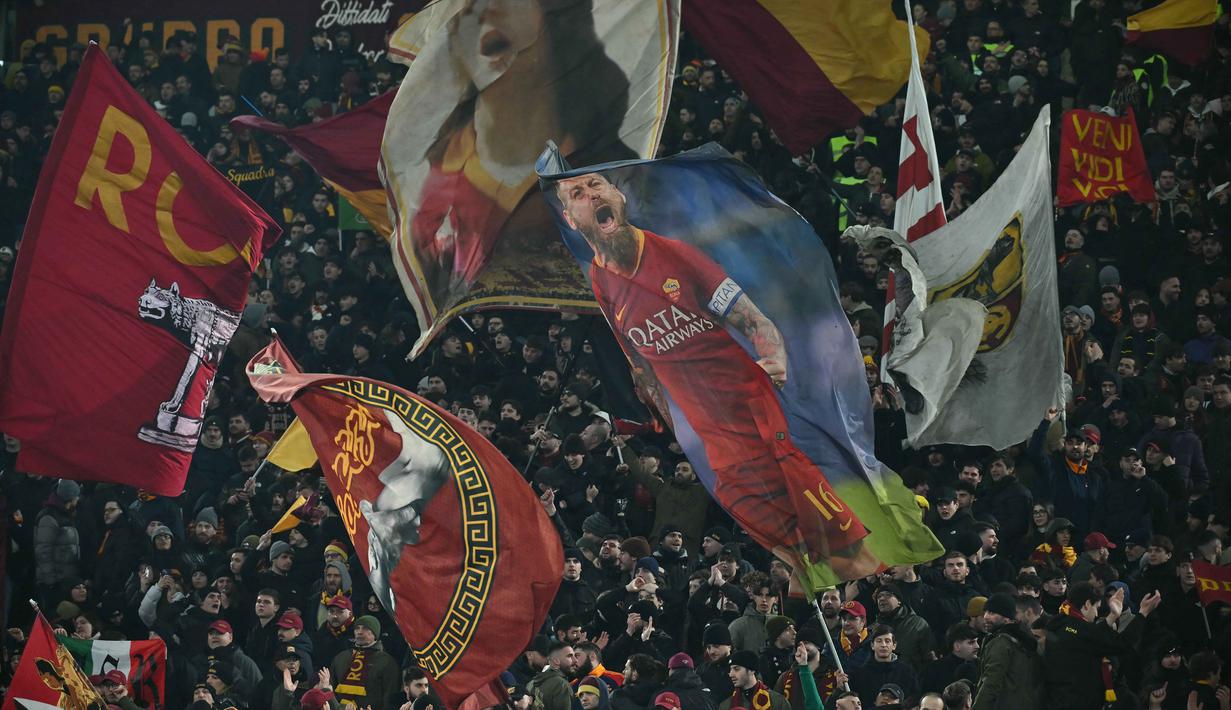Kemenangan ini membawa Giallorossi menempati peringkat keempat klasemen Liga Italia dengan 33 poin dari 17 pertandingan atau tiga poin di bawah Inter Milan yang berada di posisi puncak. Tampak daam foto, para pendukung mengibarkan bendera di akhir pertandingan sepak bola Serie A Italia antara AS Roma dan Genoa di Stadio Olimpico pada Senin 29 Desember 2025 waktu setempat atau Selasa (30/12/2025) dini hari WIB. (Filippo MONTEFORTE/AFP)