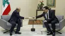 PM Lebanon, Hassan Diab (kanan) mengajukan pengunduran dirinya kepada Presiden Michel Aoun di istana presiden di Baabda, ibu kota Beirut pada 10 Agustus 2020. Pengunduran diri Diab dilakukan di tengah kemarahan rakyat atas ledakan besar di Beirut pada 4 Agustus lalu. (HO/DALATI AND NOHRA/AFP)