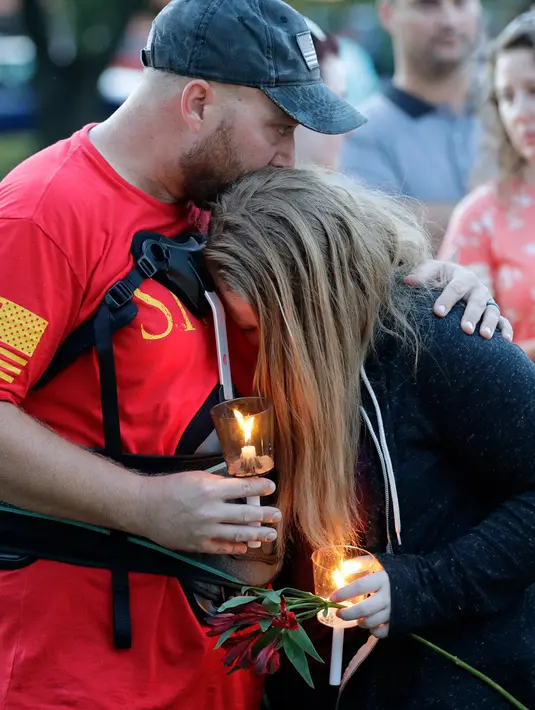Jared (kiri) memeluk putrinya, Kylie Trochesset (kanan) saat berdoa untuk mengenang korban penembakan di sekolah Santa Fe, Texas, Amerika serikat, Jumat (18/5). Pelaku diidentifikasi bernama Dimitrios Pagourtzis berusia 17. (AP Photo/David J Phillip)