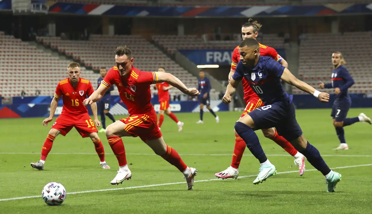 Pemain Prancis Kylian Mbappé berlari dengan bola melewati pemain Wales Connor Roberts pada pertandingan persahabatan di Stadion Allianz Riviera, Nice, Prancis, Rabu (2/6/2021). Prancis membantai Wales 3-0. (AP Photo/Daniel Cole)