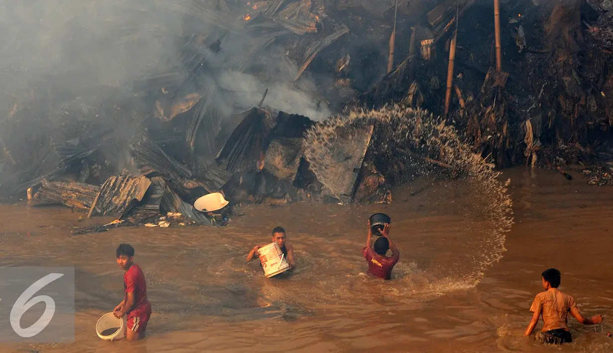 Beberapa warga berusaha menyiramkan air sungai saat terjadinya kebakaran yang melanda rumah hunian semi permanen di bantaran sungai anak kali ciliwung, Kawasan Kampung Berland, Jakarta, Rabu (2/9/2015). (Liputan6.com/Johan Tallo)