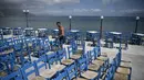 Seorang karyawan menyiapkan teras di Kissamos, barat laut Pulau Kreta, Yunani, Kamis (13/5/2021). Yunani mempermudah langkah-langkah terkait COVID-19 dalam menyambut turis internasional pada 14 Mei. (Louisa GOULIAMAKI/AFP)