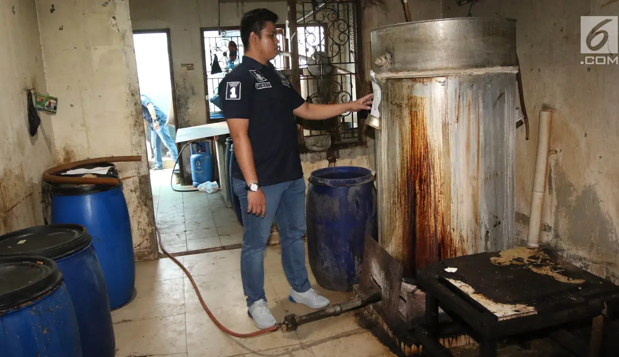 Petugas polisi dari Reskrimsus menunjukan drum tempat pembuatan ciu saat menggelar rilis di kawasan Pekojan, Tambora, Jakarta (3/5). (Liputan6.com/Arya Manggala)