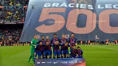 Pemain Barcelona berpose dengan latar belakang spanduk besar penghormatan untuk Lionel Messi yang telah mencetak 500 gol untuk klubnya sebelum pertandingan liga Spanyol antara Barcelona vs Osasuna di stadion Camp Nou, Barcelona (26/4). (AFP/Lluis Gene)