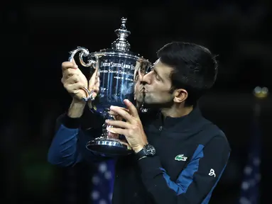 Petenis Serbia, Novak Djokovic mencium trofi turnamen AS Terbuka setelah mengalahkan Juan Martin del Potro dari Argentina pada partai final di New York, Minggu (9/9). Djokovic menang tiga set langsung 6-3, 7-6 (4), 6-3. (MATTHEW STOCKMAN/GETTY IMAGES/AFP)