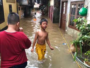 Anak-anak bermain di tengah banjir yang merendam kawasan Kebon Pala, Jakarta Timur, Selasa (25/2/2020). Akibat banjir yang tak kunjung surut, aktivitas warga di kawasan tersebut menjadi terganggu, terlebih dengan adanya pemadaman listrik. (Liputan6.com/Immanuel Antonius)