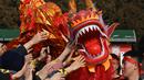 Orang-orang mencoba menyentuh seekor naga saat pertunjukan di sebuah kuil pada hari kedua Tahun Baru Imlek Naga di Beijing pada 11 Februari 2024. (GREG BAKER/AFP)