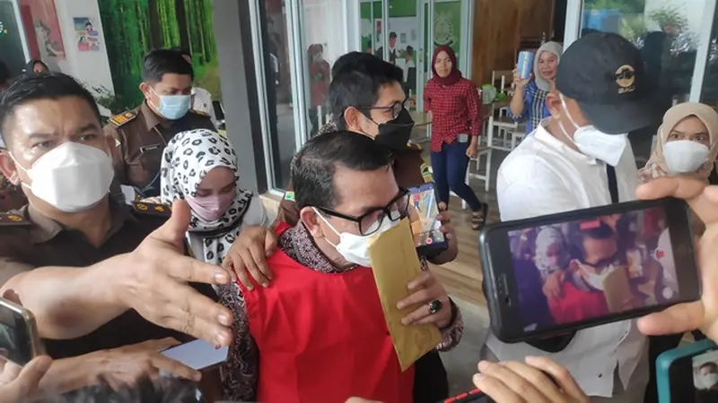 Dosen Universitas Riau Syafri Harto saat digiring petugas Kejati Riau dan Kejari Pekanbaru ke mobil tahanan.