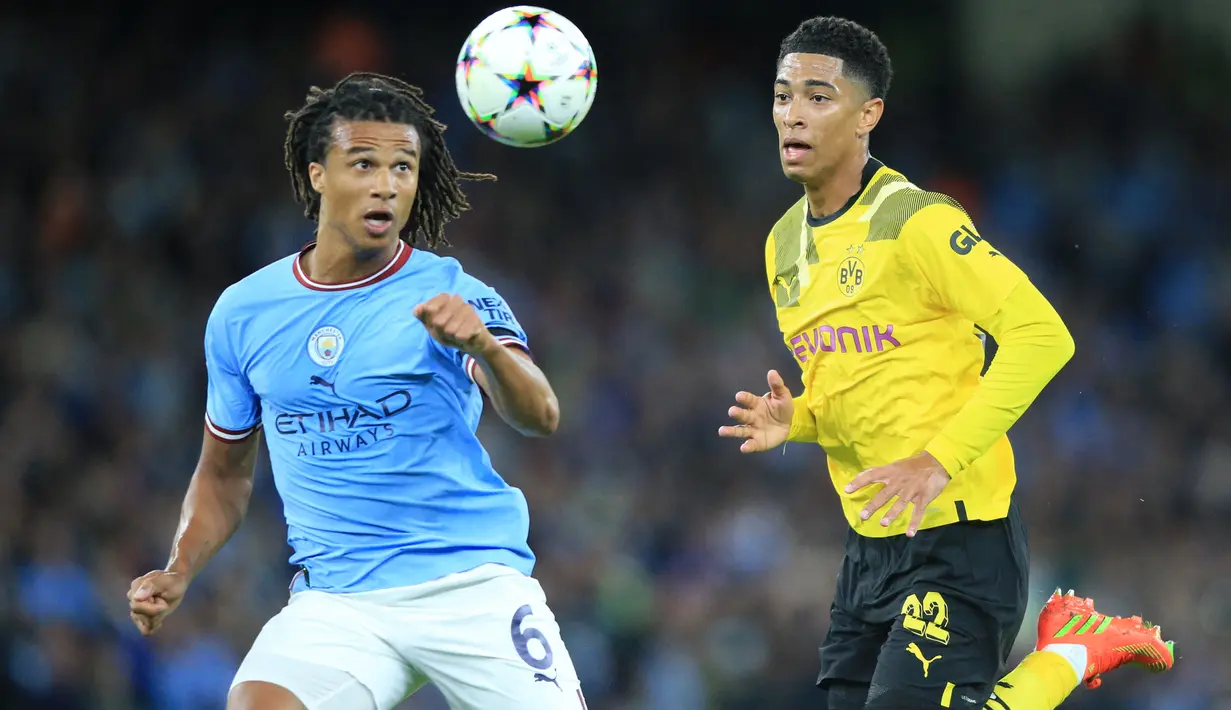 Gelandang Borussia Dortmund  Jude Bellingham (kanan) berebut bola dengan bek Manchester City Nathan Ake pada laga kedua Grup G Liga Champions di Etihad Stadium, Manchester, Kamis (15/9/2022) dini hari WIB. Menjamu Borussia Dortmund di matchday kedua Liga Champions, Manchester City menang dramatis 2-1 setelah sempat tertinggal lebih dulu. (Photo by Lindsey Parnaby / AFP)