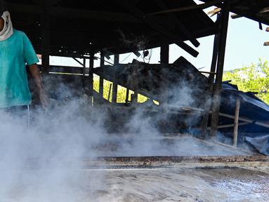 Seorang petani mengolah garam dengan cara tradisional di sebuah tambak di Lamnga, pinggiran Banda Aceh, Aceh, Selasa (7/3/2023). Petani di Aceh masih mengandalkan pola produksi tradisional, yakni sistem rebus. (CHAIDEER MAHYUDDIN/AFP)