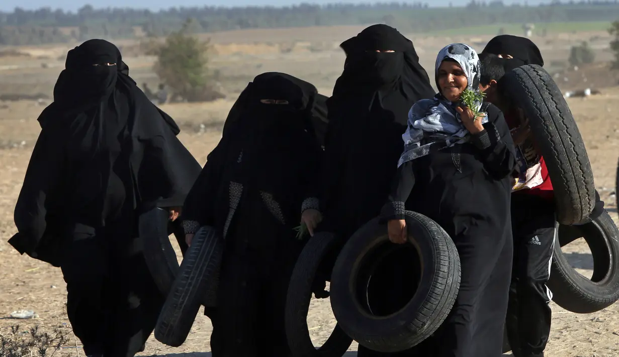 Pengunjuk rasa wanita Palestina membawa ban untuk dibakar saat bentrokan dengan tentara Israel di Khan Younis, perbatasan Gaza, Jumat (10/8). (AP Photo/Adel Hana)
