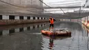 Petugas PPSU membersihkan sampah yang tertutup jaring hitam di Kali Item, Kemayoran, Jakarta, Jumat (20/7). Pemasangan jaring dilakukan untuk menutupi keruhnya air dan bau tak sedap di Kali Item. (Liputan6.com/Arya Manggala)