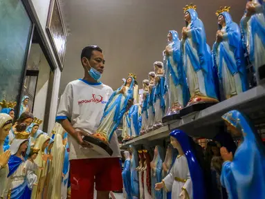 Seorang pekerja menata patung Bunda Maria yang terbuat dari fiberglass di sebuah rumah produksi di Yogyakarta pada 18 Desember 2024. (DEVI RAHMAN/AFP)