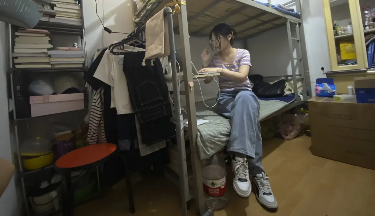 Lulusan perguruan tinggi baru-baru ini Liu Qian bekerja di komputer laptopnya di kamar yang dia sewa di sebuah apartemen di Beijing, Kamis, 7 Juli 2022.  Liu adalah salah satu dari 11 juta lulusan baru yang putus asa untuk bekerja di pasar kerja yang suram karena lockdown COVID memaksa pabrik, restoran, dan pengusaha lainnya untuk tutup. Para penyintas memotong pekerjaan dan upah. (AP Photo/Olivia Zhang)