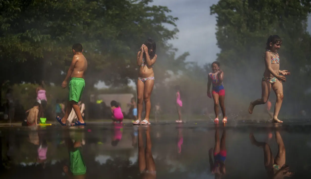 <p>Anak-anak bersantai di Taman Madrid Rio, Madrid, Spanyol, 12 Juli 2023. Lebih dari 10 wilayah Spanyol berada dalam siaga merah untuk hari kedua gelombang panas terbaru, dengan suhu mencapai 40 derajat Celcius. (AP Photo/Manu Fernandez)</p>