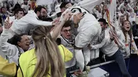 Penyerang Real Madrid asal Maroko #21, Brahim Diaz, melompat ke tribune untuk merayakan gol bersama para pendukungnya setelah mencetak gol kedua bagi timnya dalam pertandingan leg pertama babak 16 besar Liga Champions UEFA antara Real Madrid CF dan Club Atletico de Madrid di stadion Santiago Bernabeu di Madrid, Kamis dini hari WIB (5-3-2025). (Thomas COEX /AFP)