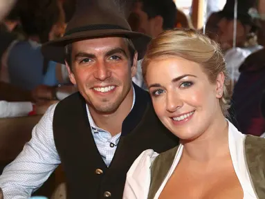 Kapten Bayern Munchen, Philipp Lahm bersama istrinya Claudia tersenyum saat menghadiri acara Oktoberfest di Munich, Jerman (2/9). (REUTERS/Alexander Hassenstein)