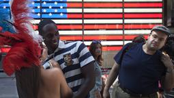 Seorang wanita berpose bersama seorang wisatawan dipinggiran ruas jalan Times Square, New York,AS,  Selasa (18/8/2015). Mereka meminta uang kepada para wisatawan yang ingin mengajak foto bersama dengan tanpa memakai busana. (REUTERS/Carlo Allegri)