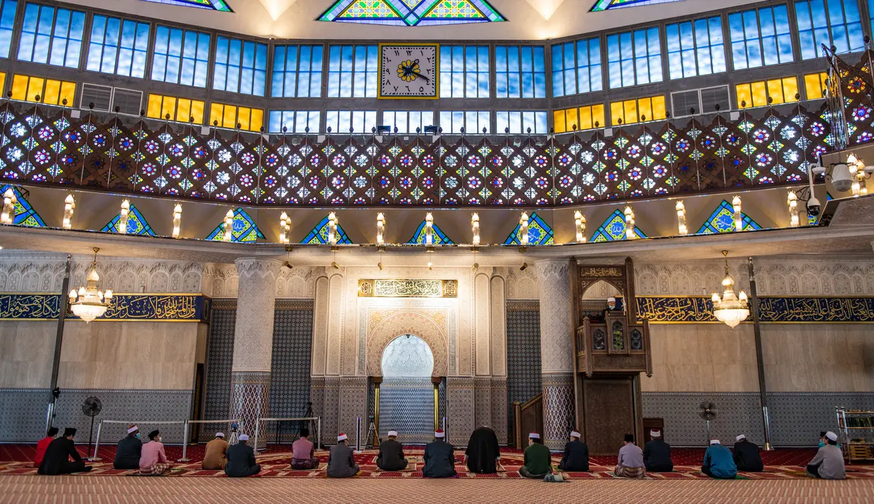 Petugas masjid mendengarkan khotbah salat Jumat dengan menerapkan jaga jarak aman saat Ramadan di Masjid Negara Malaysia, Kuala Lumpur, Malaysia, Jumat (15/5/2020). Masjid Negara Malaysia kembali dibuka setelah pemerintah setempat melonggarkan lockdown akibat pandemi COVID-19. (Mohd RASFAN/AFP)