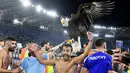 Tak mau ketinggalan, mantan pemain AS Roma yang kini berseragam Lazio yakni Pedro pun ikut merayakan kemenangan bersama burung Elang di depan para pendukung Biancocelesti yang bersorak. (AFP/Vincenzo Pinto)