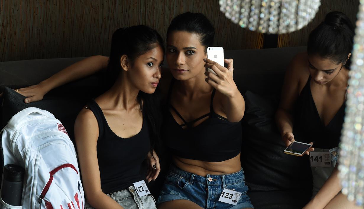 Model berselfie saat menunggu untuk tampil di hadapan juri selama audisi model Lakme Fashion Week (LFW) di Mumbai (13/6). Sekitar 153 model India dan internasional berpartisipasi untuk audisi koleksi LFW Winter/Festive 2017. (AFP Photo/Punit Paranjpe)