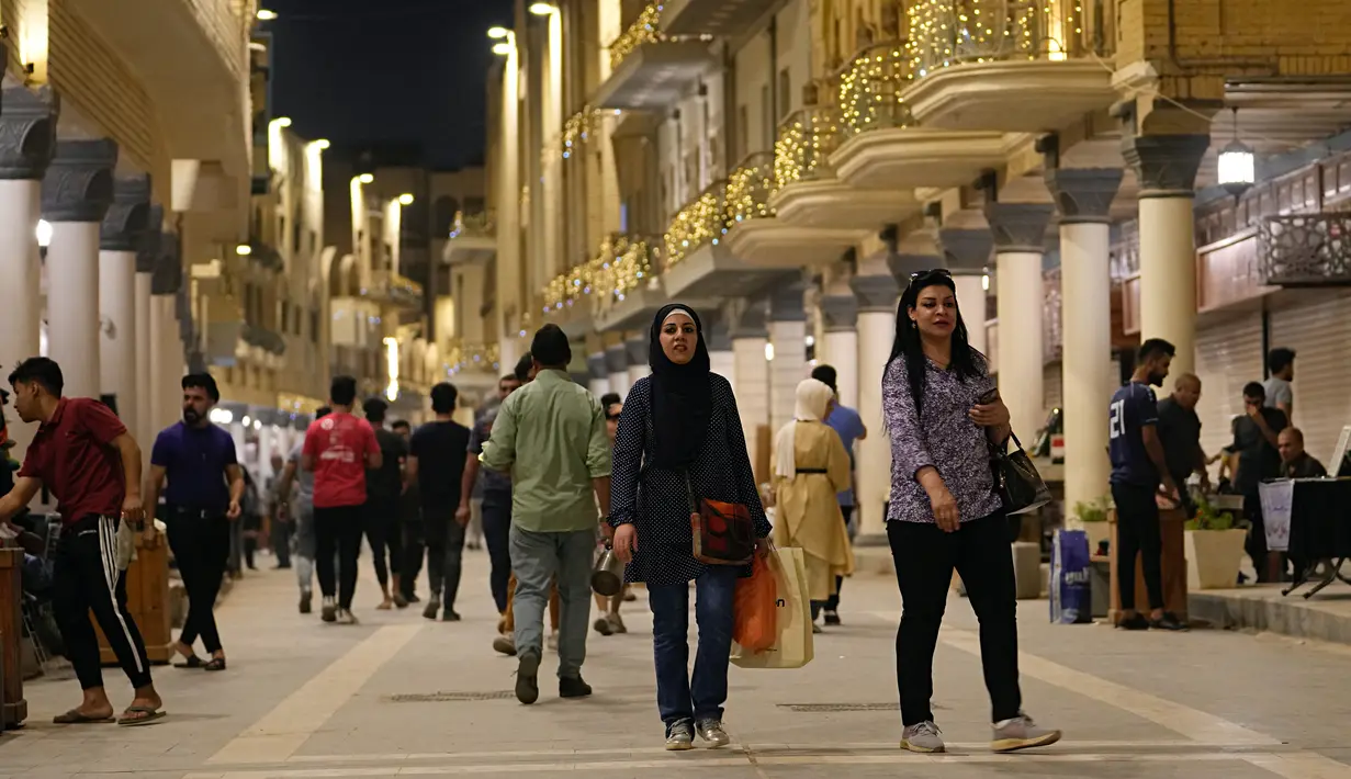 Warga Irak berjalan melalui pasar buku di Jalan Mutanabi Baghdad, Irak (18/5/2022). Jalan ini disebut sebagai jantung dan ruh literasi dan komunitas intelektual Baghdad. (AP Photo/Hadi Mizban)