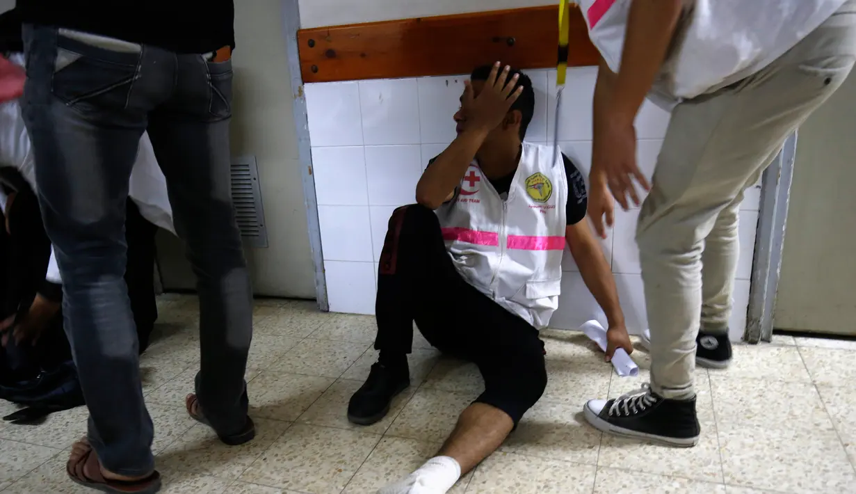 Seorang perawat pria duduk sambil menangis atas kematian rekannya Razan al-Najjar di kamar jenazah di rumah sakit Khan Yunis di Jalur Gaza selatan (1/6). Razan tewas ditembak oleh tentara Israel di dekat pagar perbatasan Gaza. (AFP Photo/Kata Khatib)