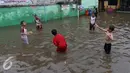 Beberapa anak bermain bola diatas genangan air di kawasan Jatayu, Jakarta, Senin (21/11). Genangan air di kawasan ini mencapai 50 cm hingga 100 cm. (Liputan6.com/Gempur M. Surya)